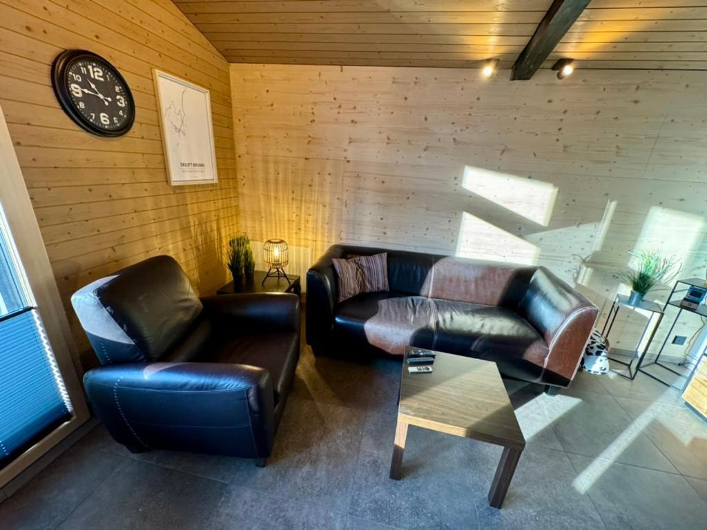 ein Wohnzimmer mit zwei Ledersofas und einer Uhr in der Unterkunft Ferienwohnung Brunni-Lodge direkt am Grossen Mythen in Alpthal