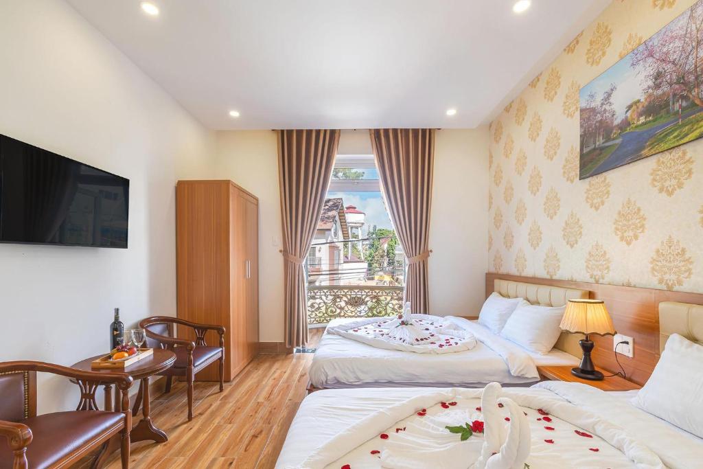 a hotel room with two beds and a television at Villa Hoa Ly Đà Lạt in Da Lat