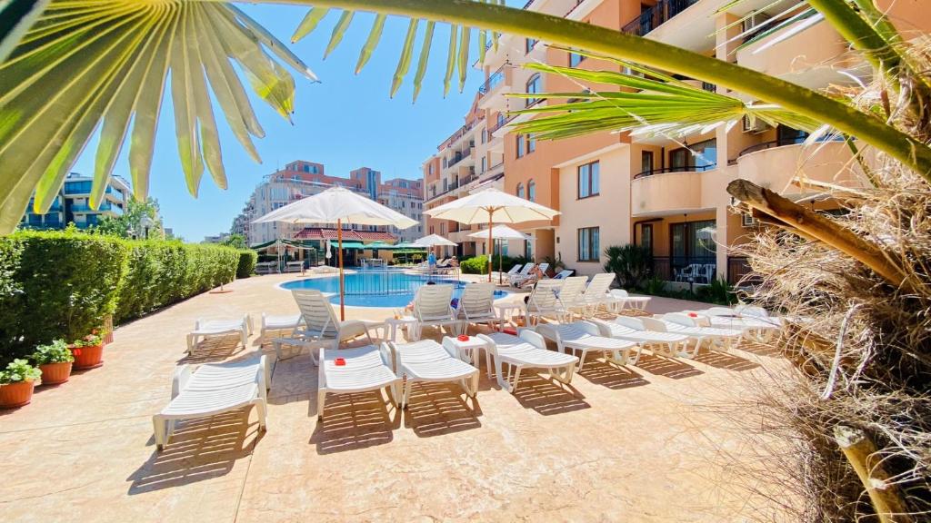 a row of lounge chairs and a swimming pool at a hotel at Bratanov Summer Apartment in Sunny Beach