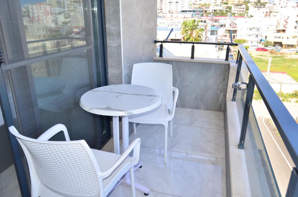 a balcony with white chairs and a table and a window at Akdeniz Yaşam Otel in Silifke