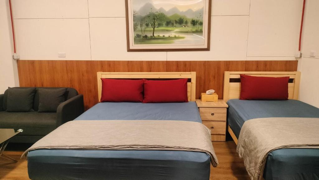 2 camas con almohadas rojas y una silla en una habitación en 水源棧 en Fengyuan