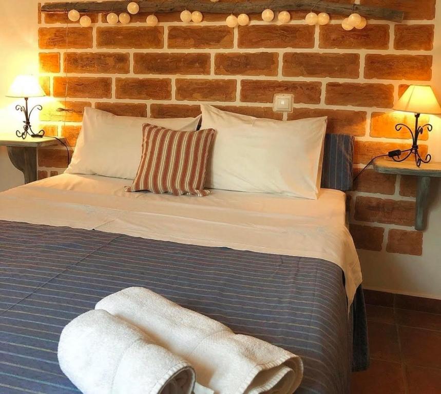 a bedroom with a bed with a brick wall at AMPELIA KYTHIRA in Livadi