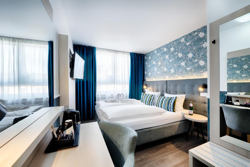 ドルトムントにあるHome Hotelのベッドとデスクが備わるホテルルームです。