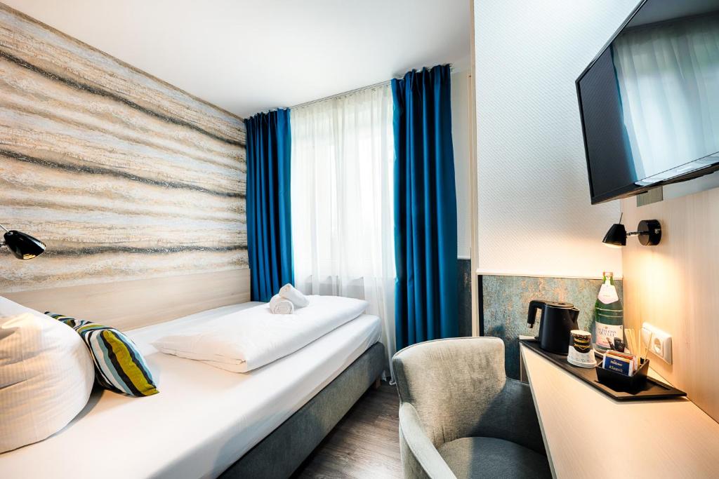 Habitación de hotel con cama y TV en Home Hotel, en Dortmund