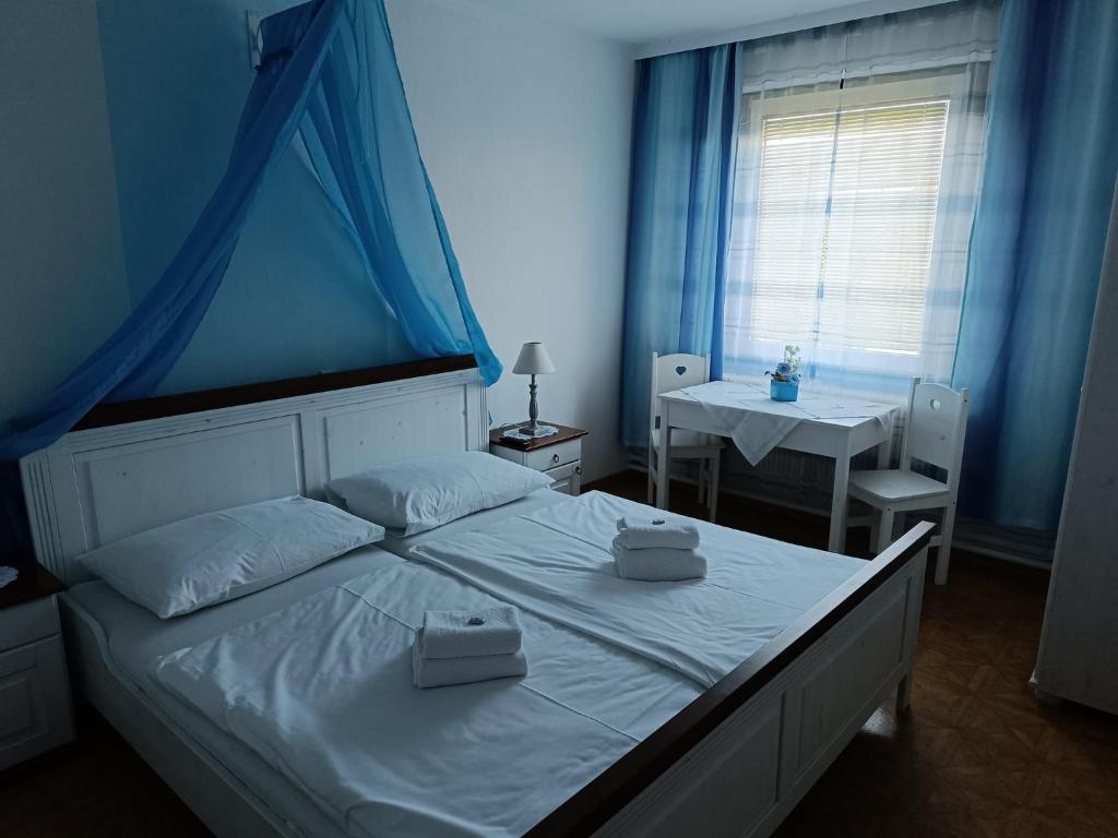 a bedroom with a white bed with a blue wall at Pension Eder in Bruck an der Leitha