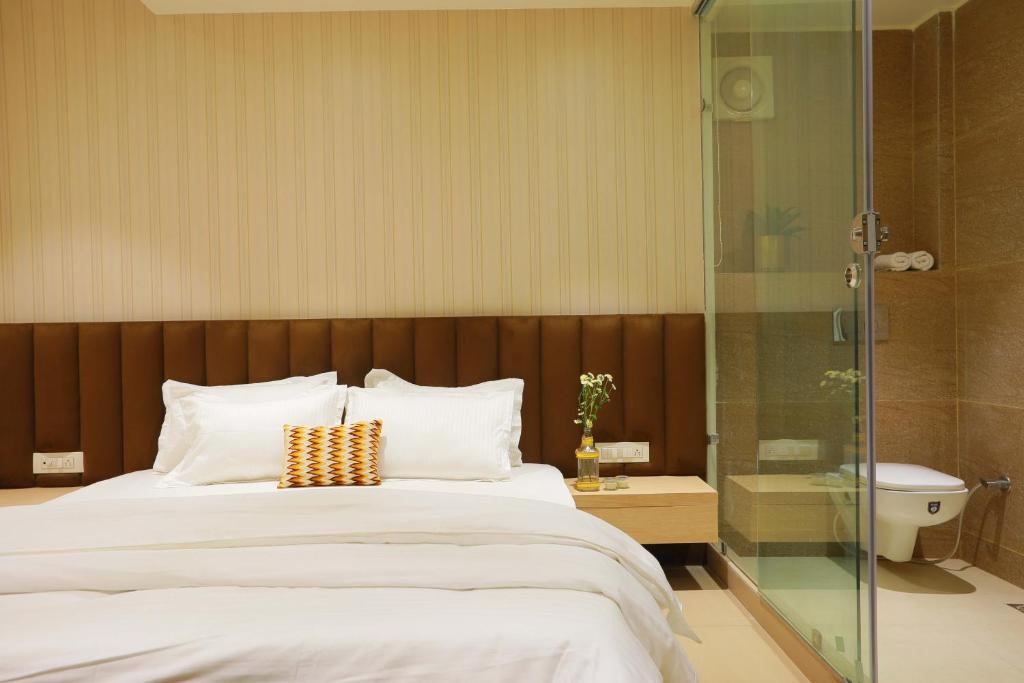 a bedroom with a bed and a glass shower at Hotel Adora in New Delhi