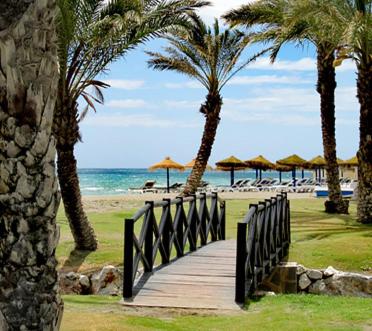 een houten loopbrug naar het strand met palmbomen bij Sea City Torremolinos Golf in Torremolinos