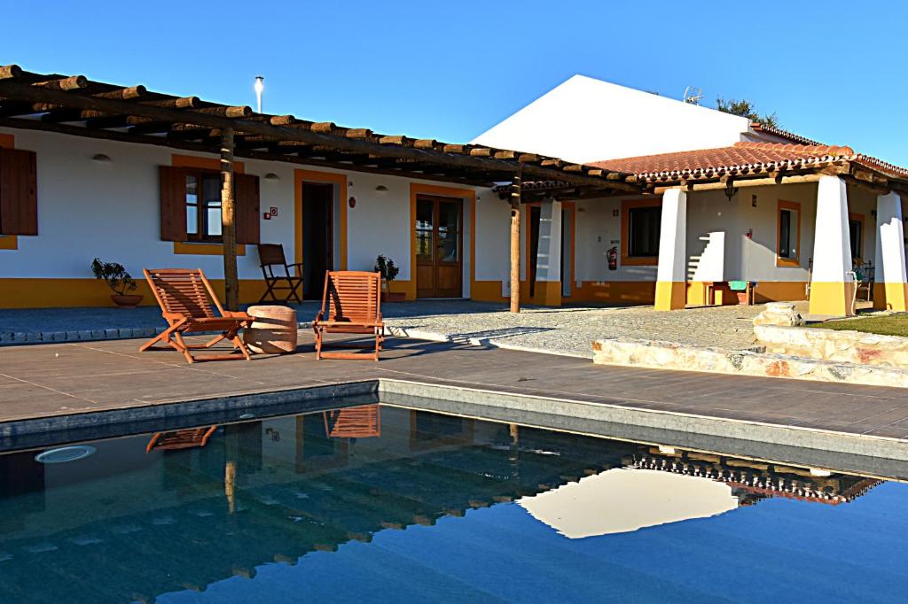 a house with two chairs and a swimming pool at Turismo Rural Pedremoura in Vila Ruiva