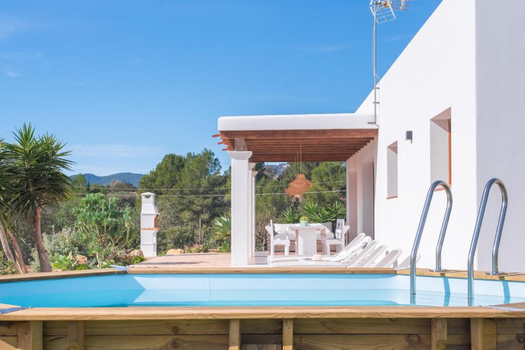 a swimming pool with a wooden deck and a house at Villa Sa Planeta in Sant Josep de Sa Talaia