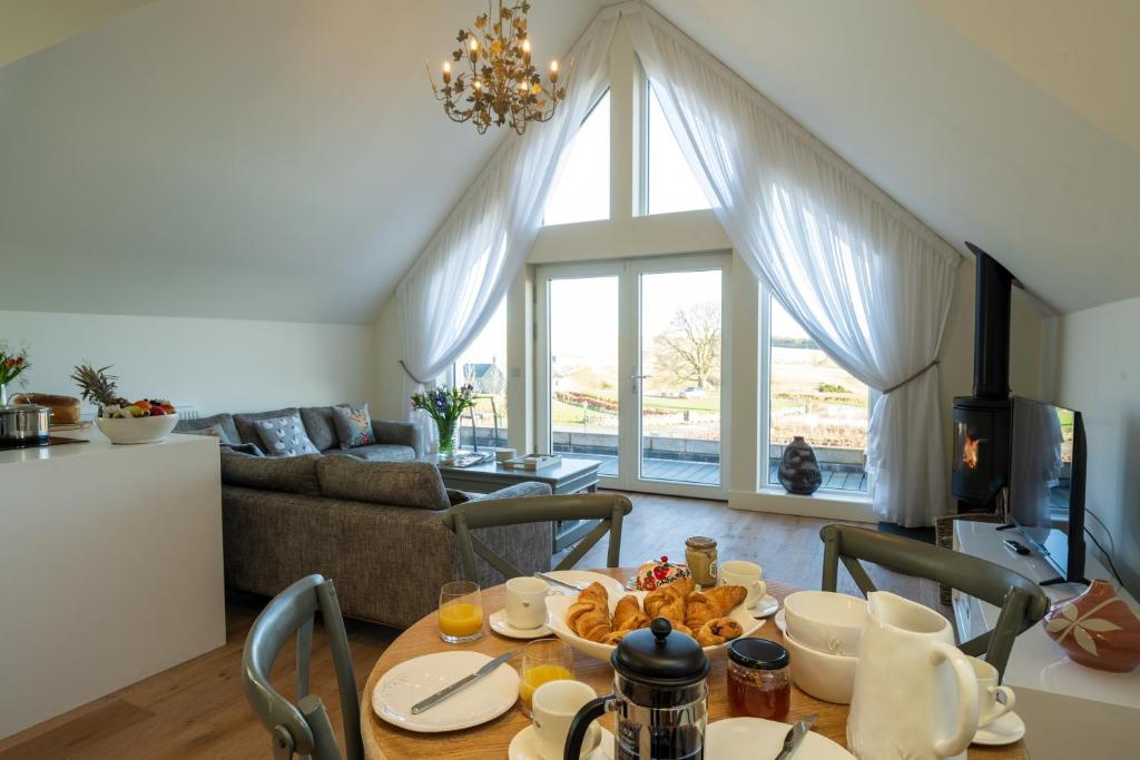 een woonkamer met een tafel met eten erop bij Capercaillie Cottage - Luxury converted steading in Perth