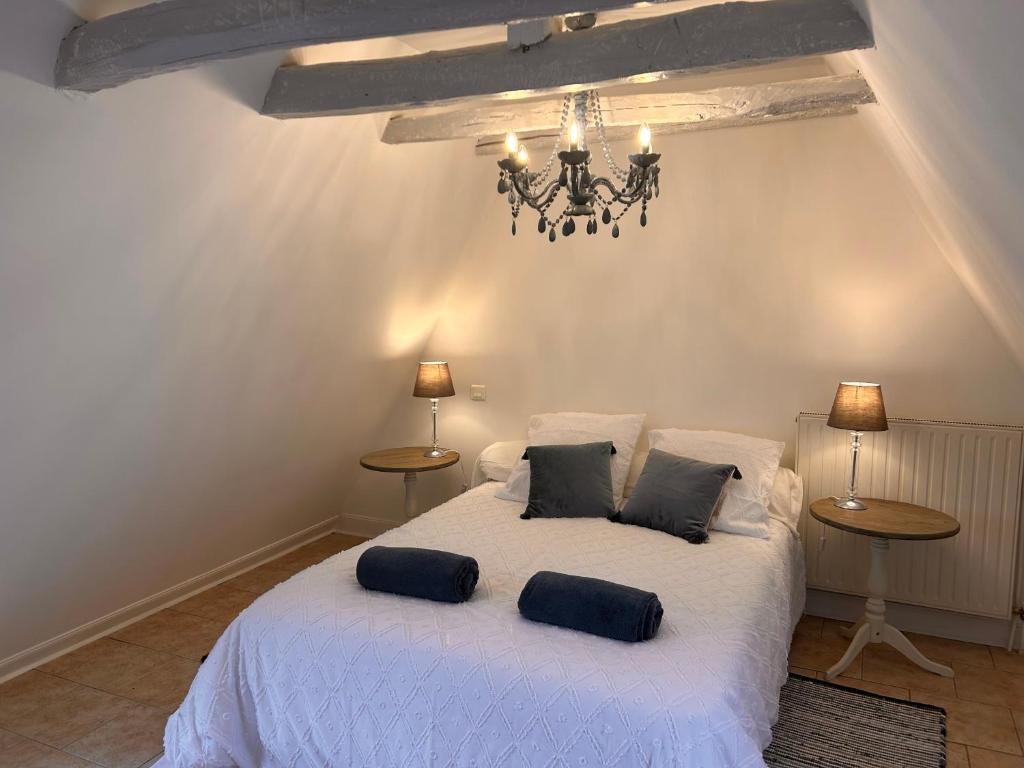 um quarto com uma cama branca com 2 mesas e um lustre em La Maison Bleue em Sarlat-la-Canéda