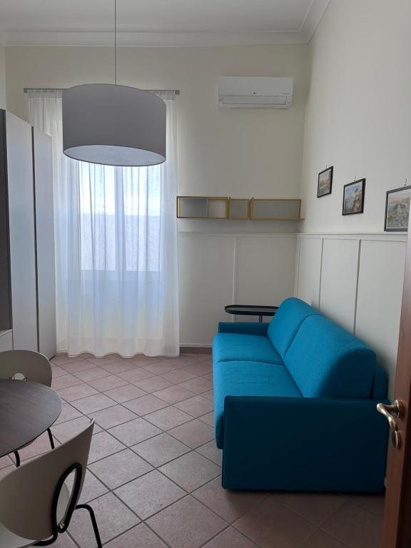 Una sala de estar con un sofá azul y una mesa. en La Casa di Ivan e Giorgia, en Pozzuoli