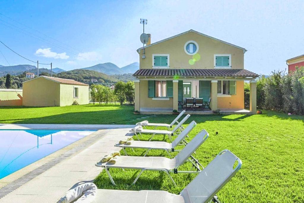 a house with chairs and a pool in front of it at Villa Gialetti in Almiros Beach