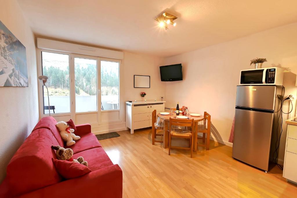 a living room with a red couch and a table at L'Ourson Randonneur - Station de ski à 600m in La Bresse