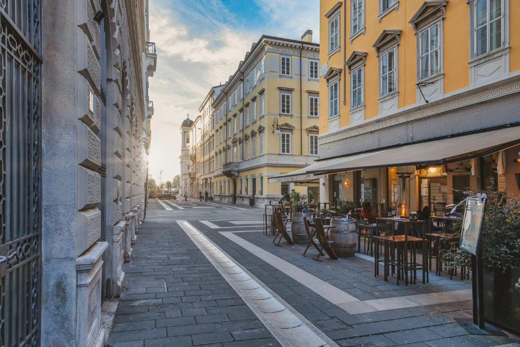 una strada cittadina vuota con tavoli, sedie ed edifici di San Nicolò Suites a Trieste