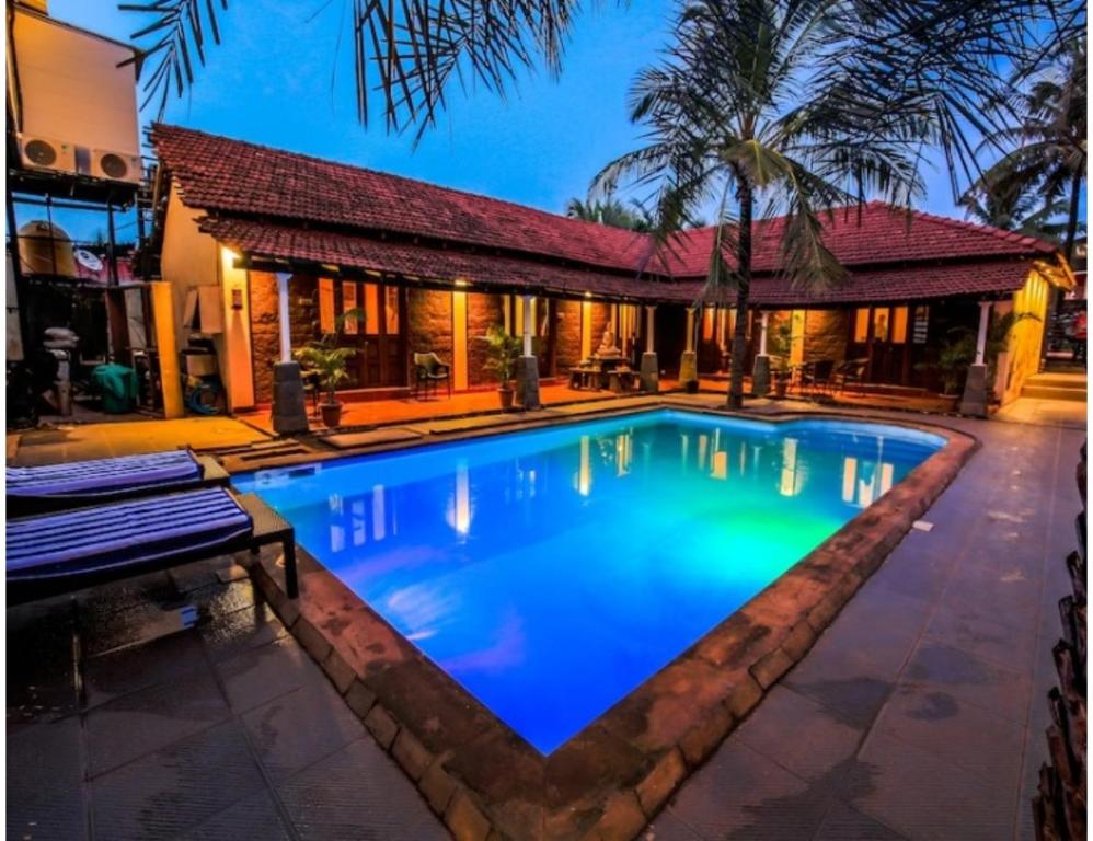 a swimming pool in front of a house at R K Habbana Beach Resort, Baga, Goa in Baga