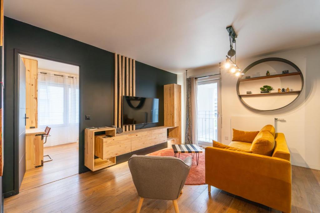 a living room with a yellow couch and a television at L'Œuvre dArt - Appartement avec parking privé in Noisy-le-Grand