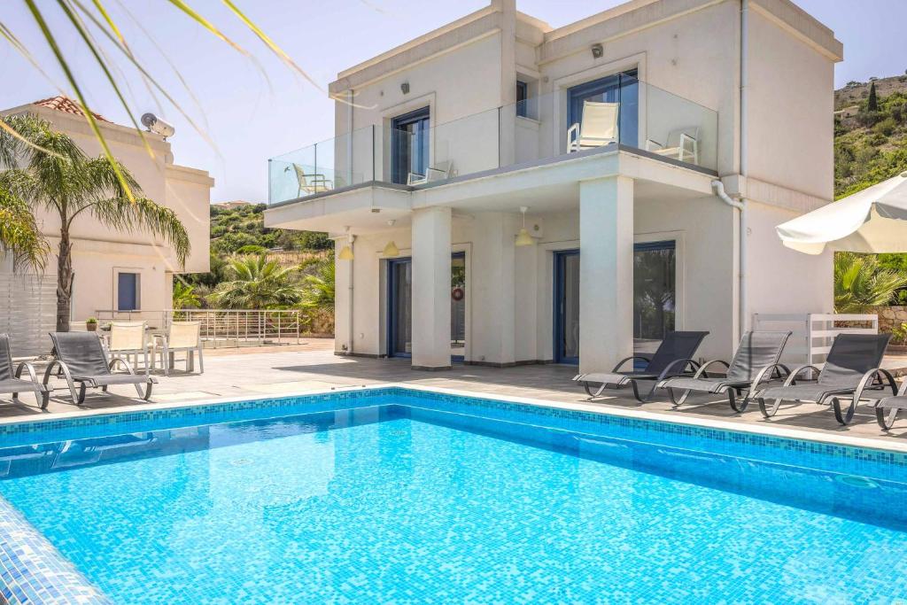 a villa with a swimming pool in front of a house at Villa Seahorse Skala in Spathíon