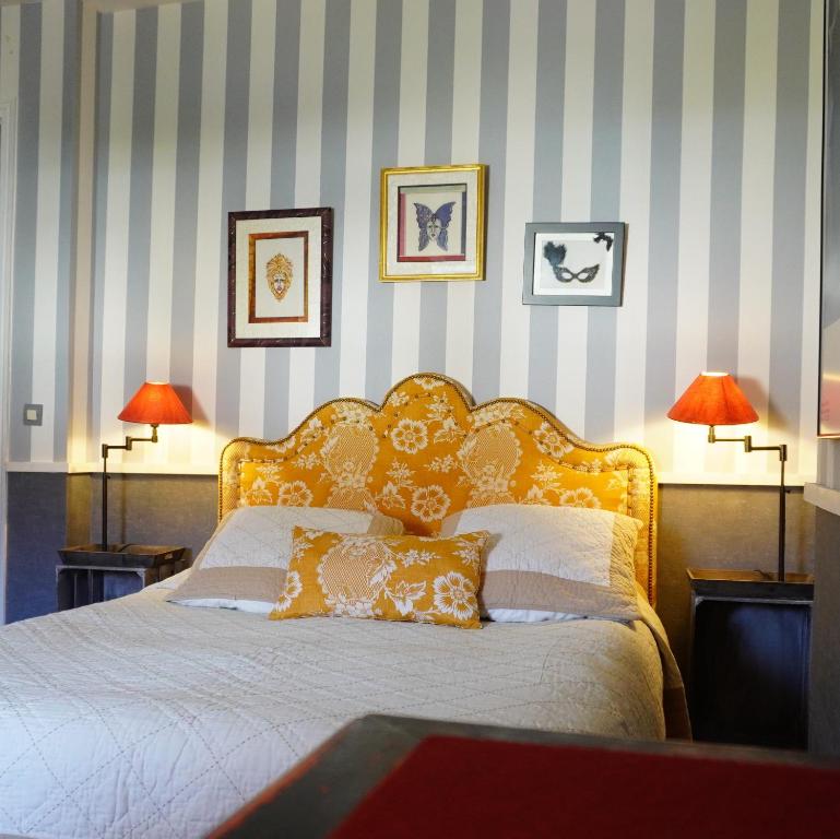 a bedroom with a bed with two lamps and a striped wall at Au Bonheur De Ce Monde in Boudreville