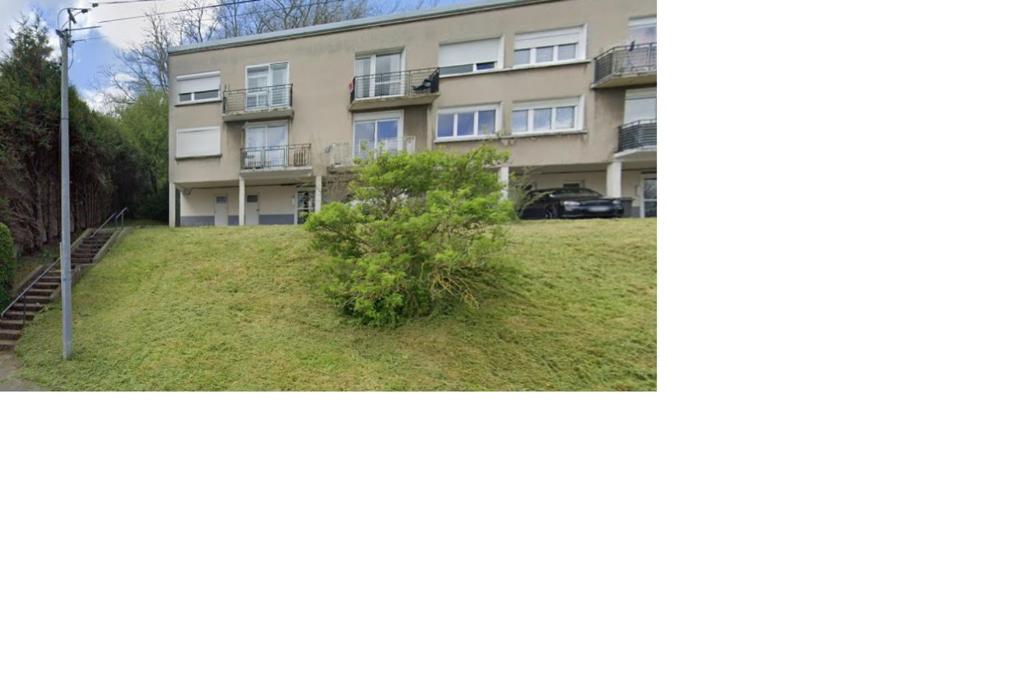 un edificio de apartamentos con un arbusto delante de él en Lumineux et proche de tout avec balcon et à côté du bois, en Boulogne-sur-Mer