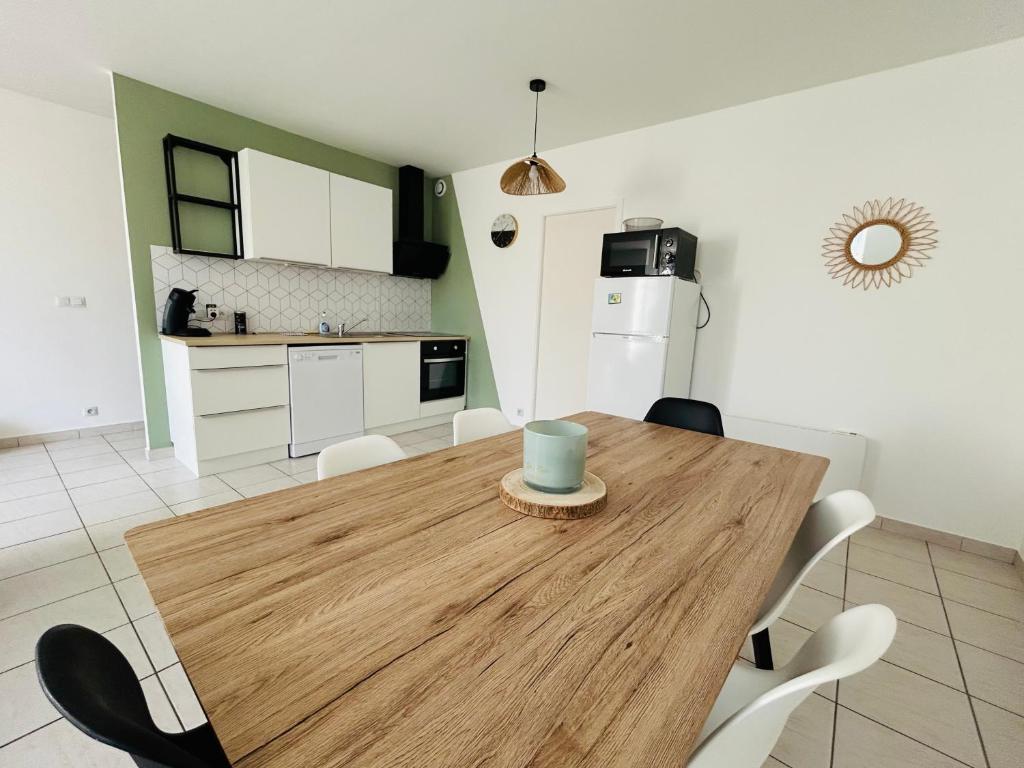 a kitchen and dining room with a wooden table and chairs at Havre de tranquillité à 13Kms des plages de Royan in Le Gua
