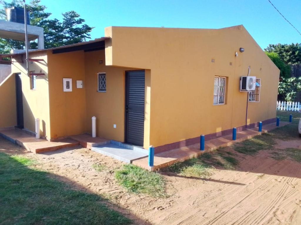 a small yellow house with a porch at Recanto do Meu Tio in Chimoio