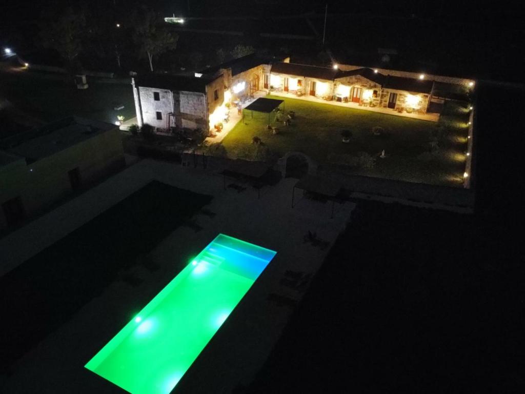 una piscina por la noche con luz verde en Agriturismo Masseria Quaremme, en Carpignano Salentino