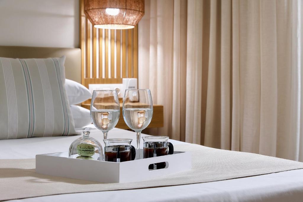 ein Tablett mit zwei Weingläsern auf dem Bett in der Unterkunft Alai Crete a Tribute Portfolio Resort in Stalida