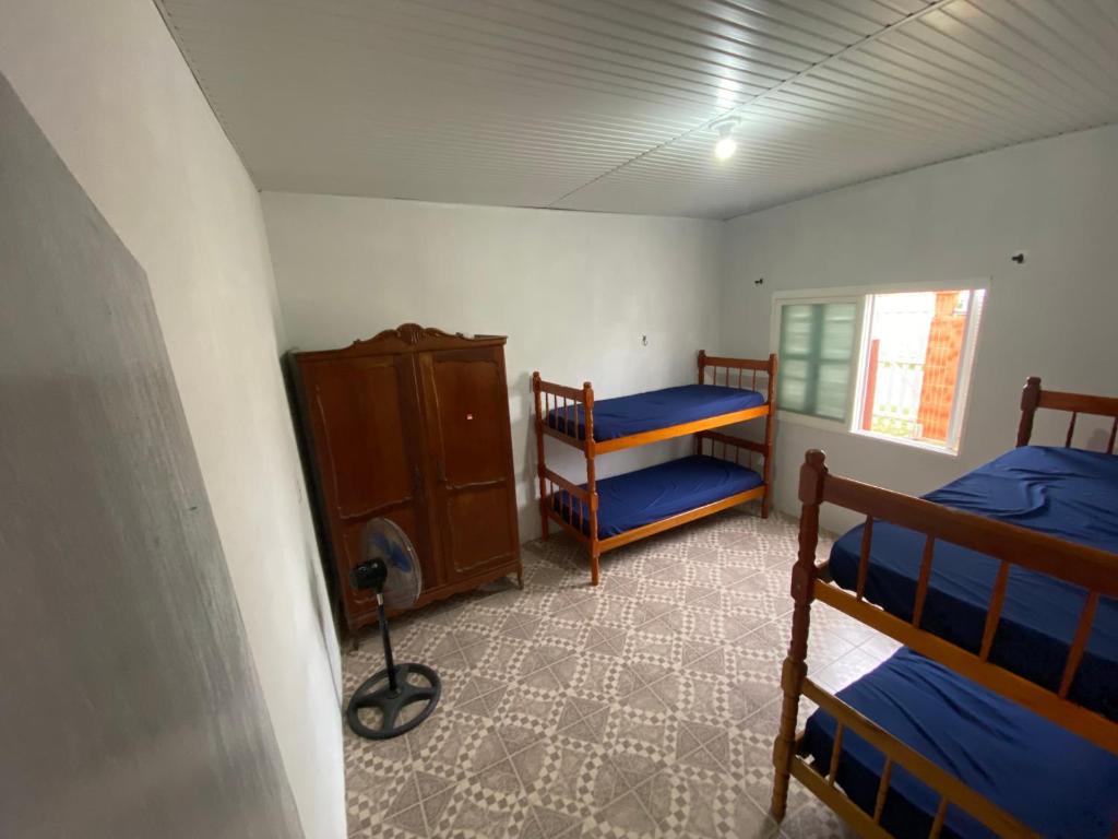 a bedroom with two bunk beds and a dresser at Casa com 2 quartos grandes a 150m da praia in Rio Grande