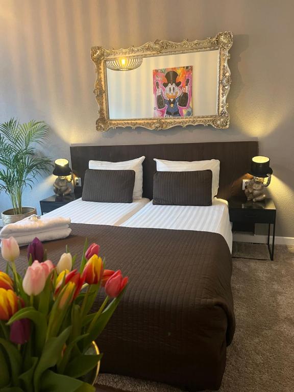 ein Schlafzimmer mit einem Bett mit einem Spiegel und Blumen in der Unterkunft Hotel Orion in Rotterdam