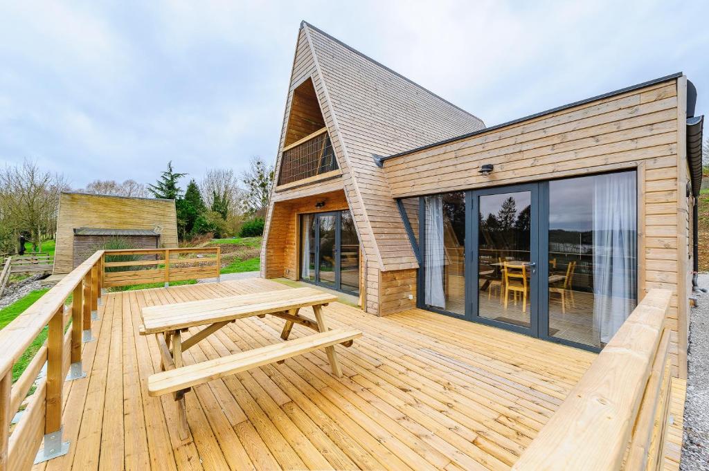 una terraza de madera con un banco de picnic y una casa en Cottage 3 chambres - Chaleureux chalet pour 6 