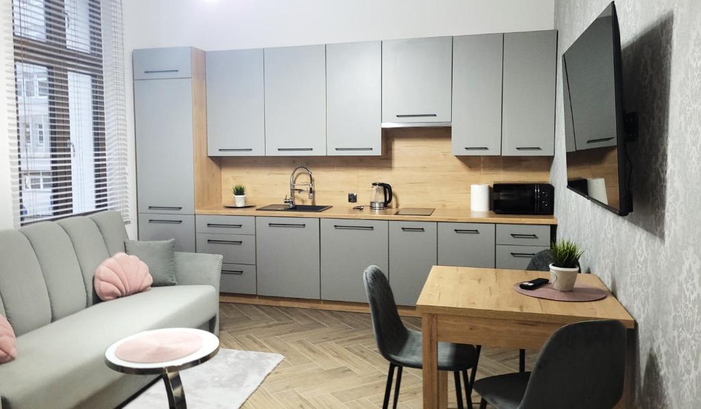 a kitchen with white cabinets and a table and a couch at APARTAMENT JARACZA 28/10 in Słupsk