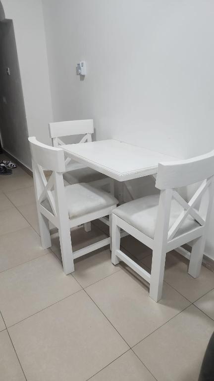 uma mesa branca e um par de cadeiras ao lado de uma mesa em Smiler's comfort em Mombasa