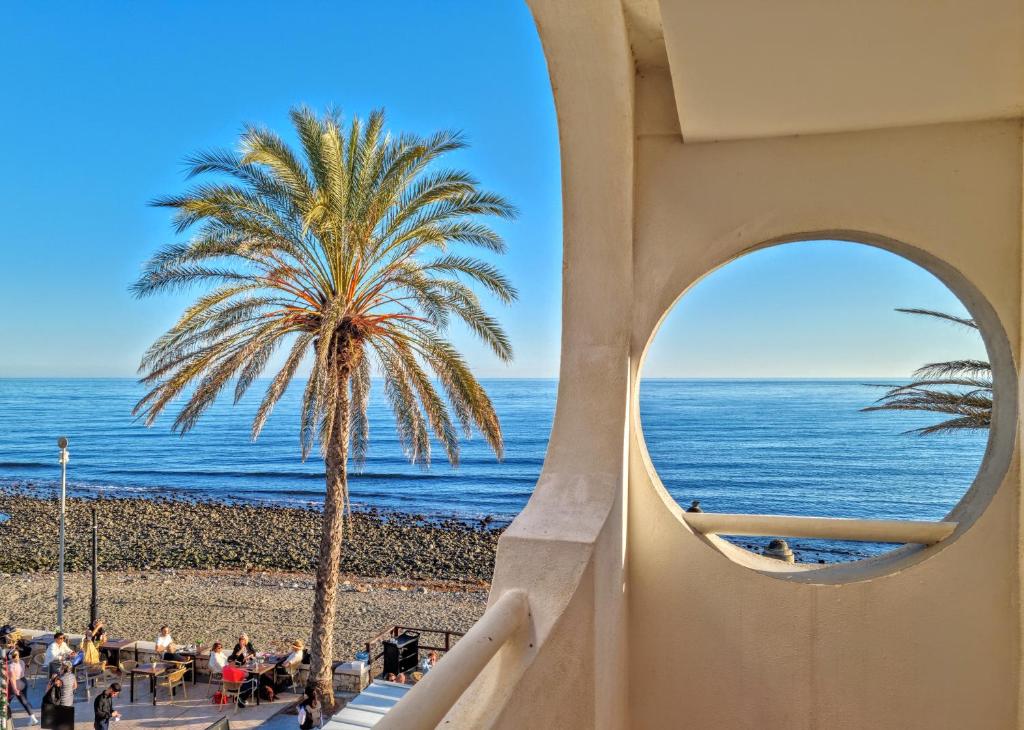 a palm tree and the ocean from a building at Buenti Apartments Beach Beautiful view in Marbella