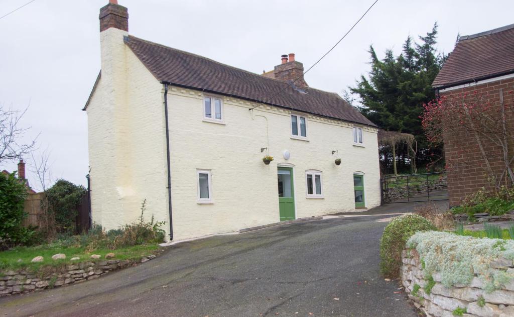a white house with green doors on a street at Mount Cottage in Shrewsbury
