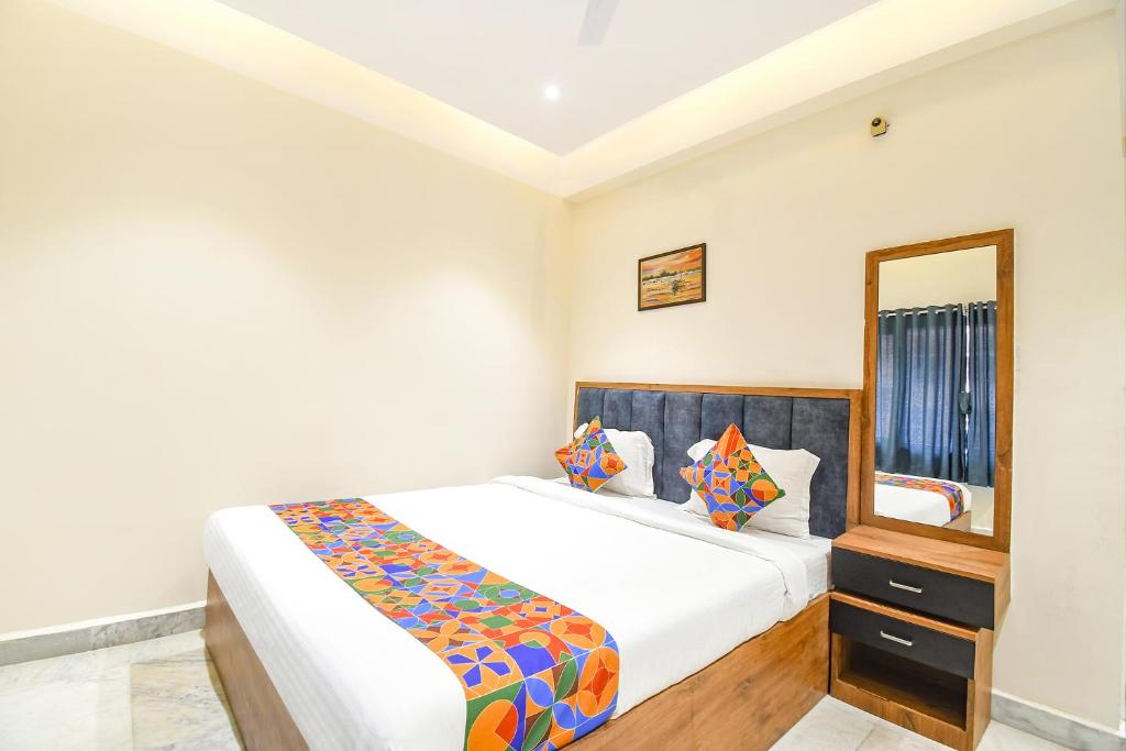 1 dormitorio con cama y espejo en FabHotel Prime The Golden Plaza, en Tarapith