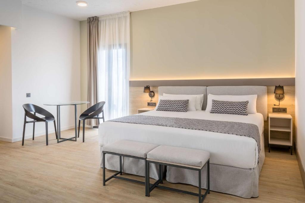 a bedroom with a bed and a table and chairs at Occidental Puerto Banús in Marbella