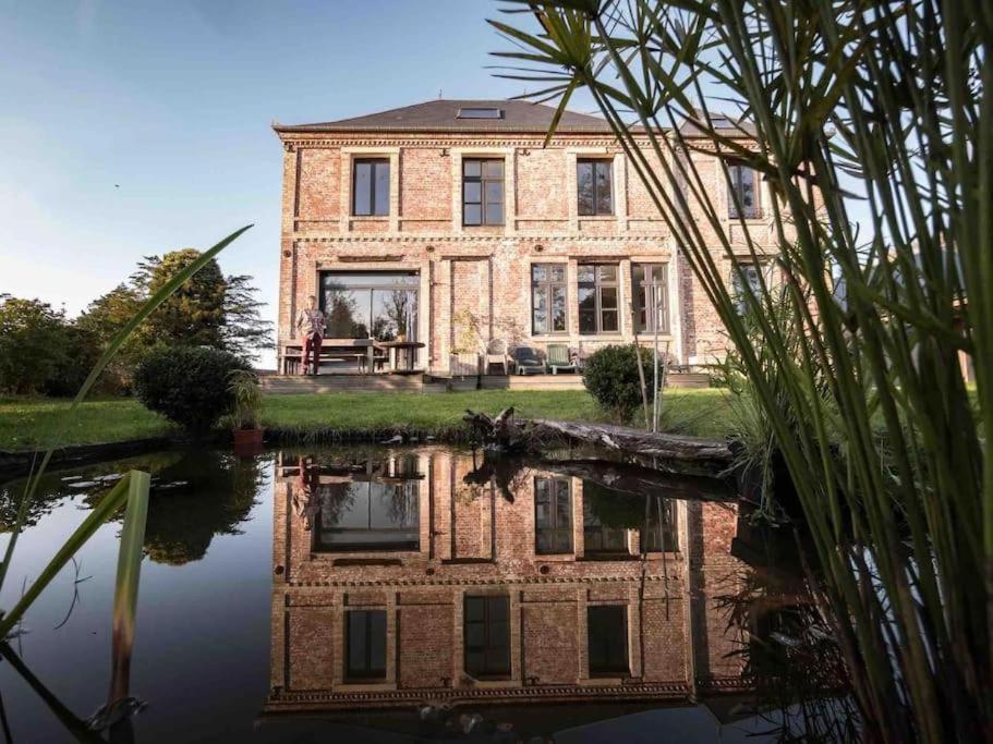 une ancienne maison en briques avec sa réflexion dans l'eau dans l'établissement Gites Au ChAtÔ et la Paillote en baie de somme, à Quend
