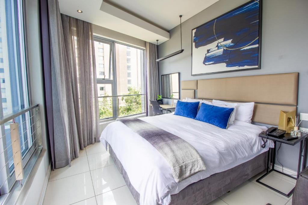 1 dormitorio con cama y ventana grande en The Capital On The Park Luxury Stay en Johannesburgo