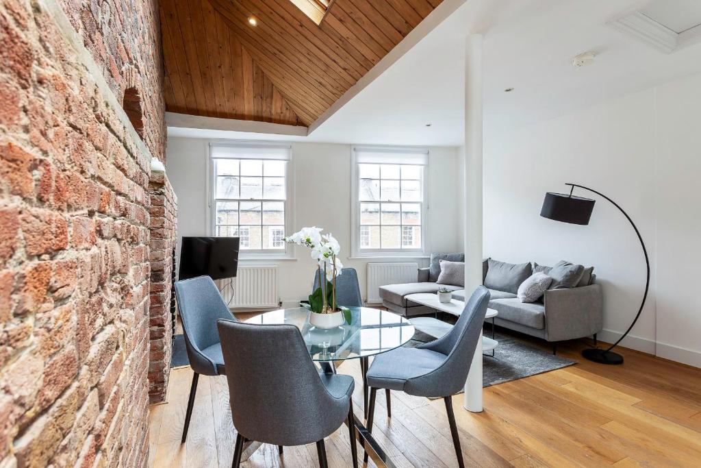 ein Wohnzimmer mit einer Ziegelwand, einem Tisch und Stühlen in der Unterkunft Bright Marylebone Apartment in London