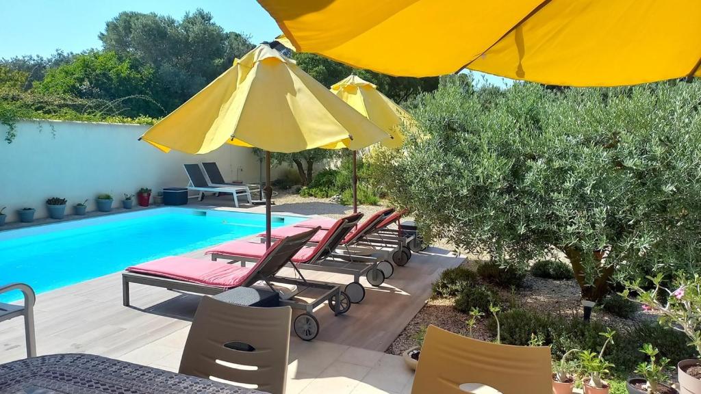 un groupe de chaises et de parasols à côté d'une piscine dans l'établissement Les Lavandins-Gite Vincent, à Saint-Rémy-de-Provence