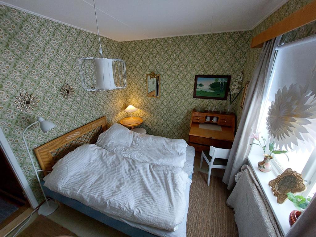 um pequeno quarto com uma cama e uma secretária em Private Room in Pink House em Pajala