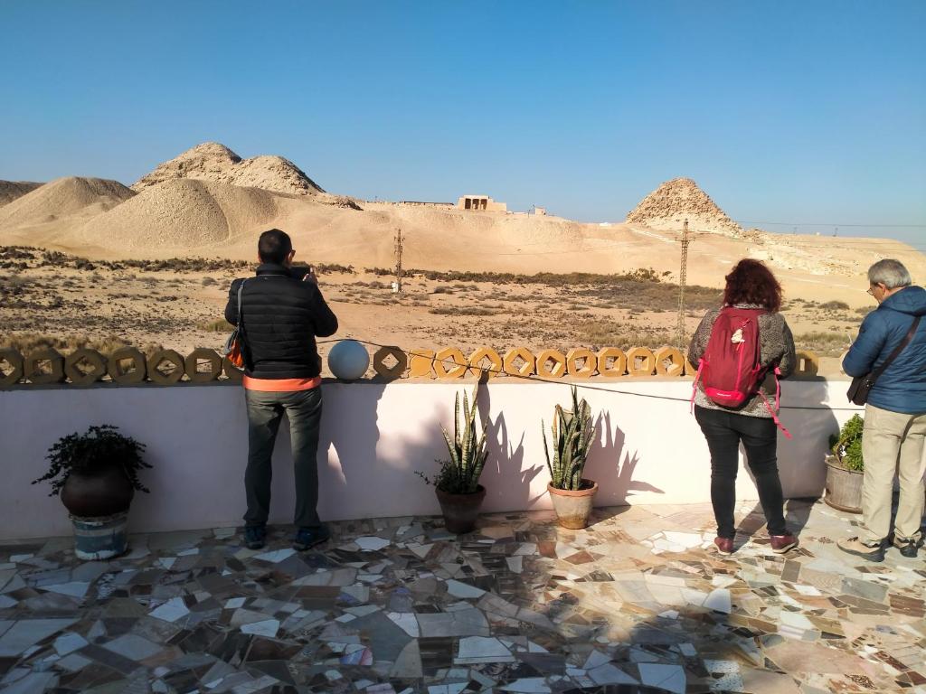 Des gens debout sur un muret regardant le désert dans l'établissement Seror Guest House, au Caire