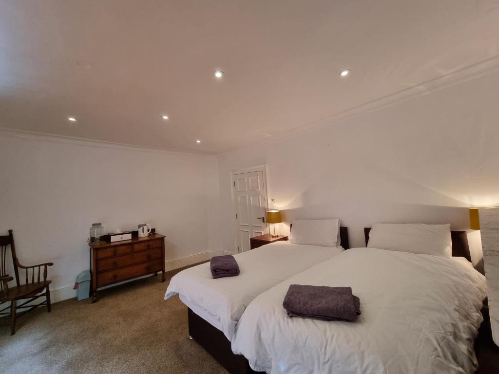 a bedroom with two beds with white sheets and a table at Firkinn in London