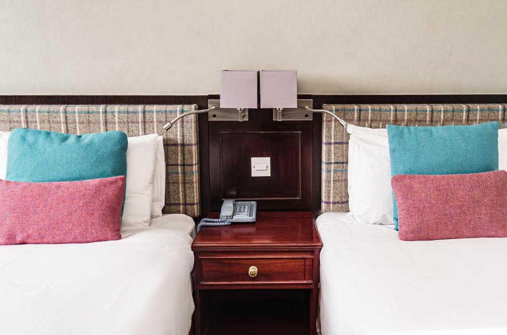 um quarto de hotel com duas camas e uma mesa com um telefone em Caladh Inn em Stornoway