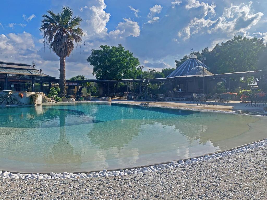 une piscine avec un palmier et un bâtiment dans l'établissement Masseria Don Vito, à Merine