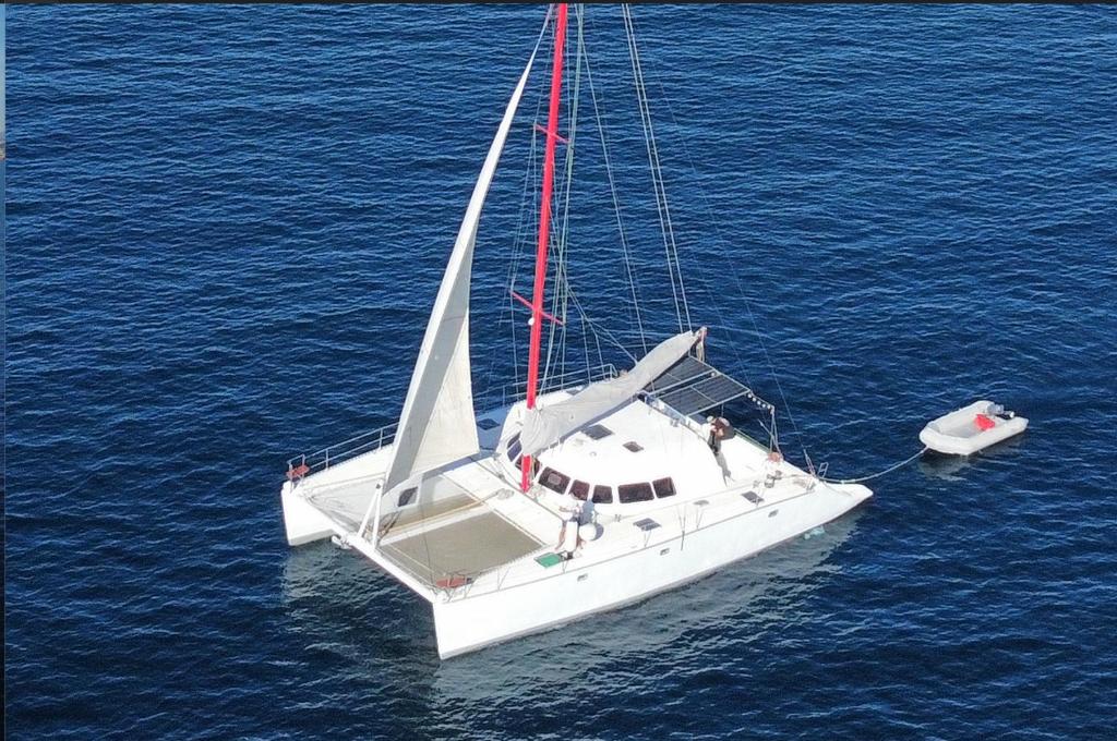 un velero blanco en el agua con dos personas en él en Catamarán Tagomago 50, en Ibiza