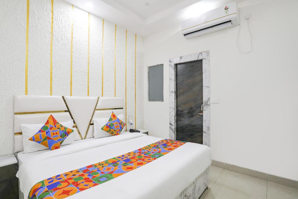 1 Schlafzimmer mit 2 weißen Betten und bunten Kissen in der Unterkunft FabExpress Mahi Ganga Heritage in Haridwar
