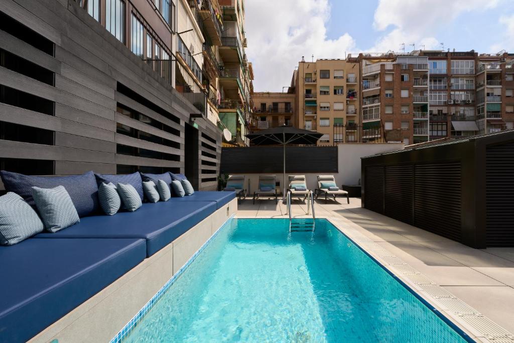バルセロナにあるカタロニア グラン ヴィア BCNの青いソファとスイミングプール付きの屋上パティオ