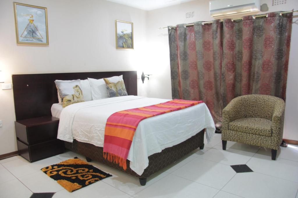 1 dormitorio con 1 cama y 1 silla en Tasha Lodge & Tours, en Livingstone